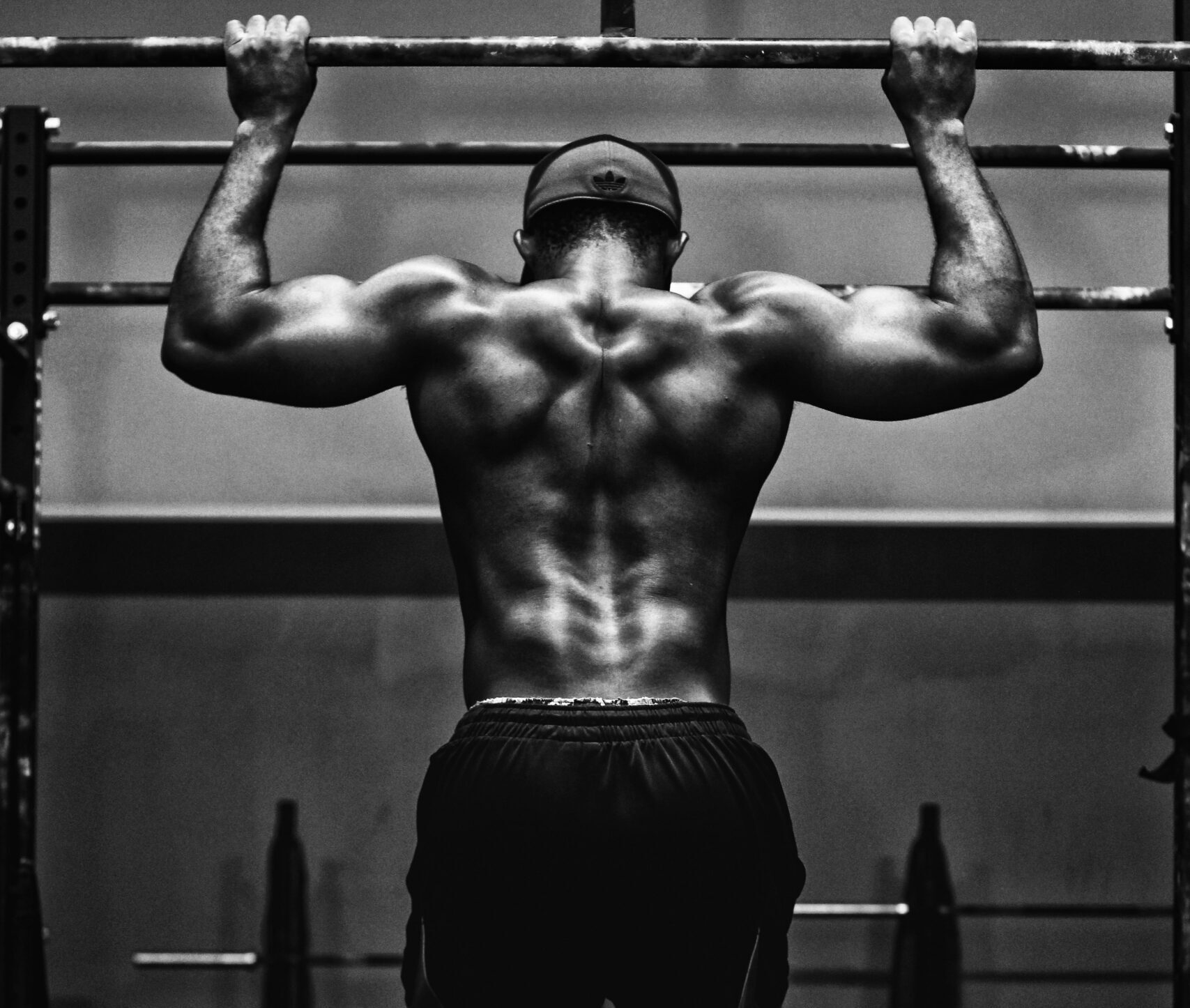 A photograph from behind of muscular person doing a pull up