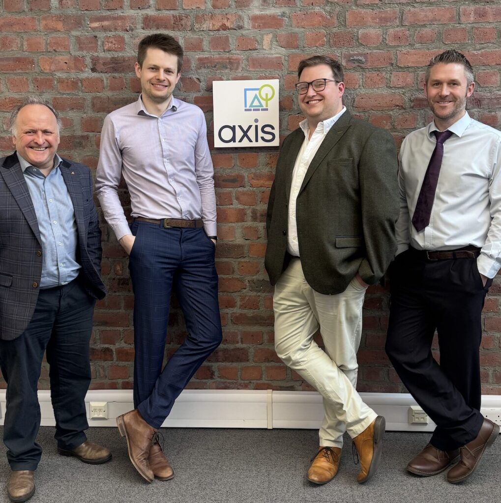 Photo shows some of the Axis team smiling in front of the company logo